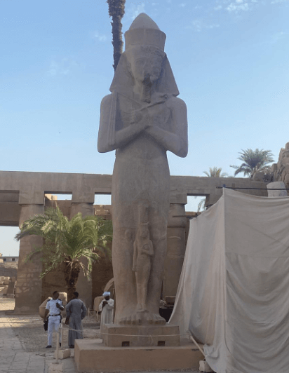 Mann bietet sich als inoffizieller Guide neben einer Statue im Luxor-Tempel an
