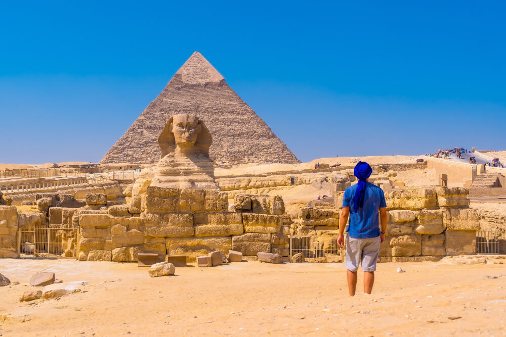 Urlauber vor der Sphinx und einer der Pyramiden von Gizeh