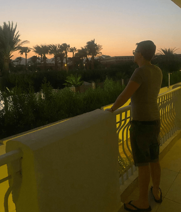 Mann mit kurzer Hose auf Balkon eines Resorts in Ägypten, typische Sommerkleidung im Hotel