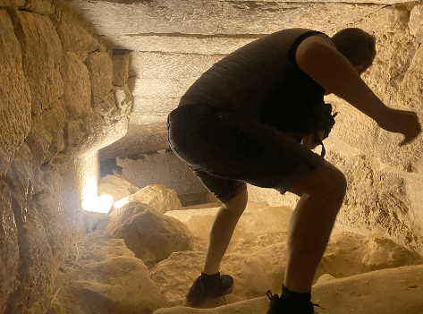 Mann steht im Inneren eines Schachts der Pyramiden von Gizeh mit kurzer Hose