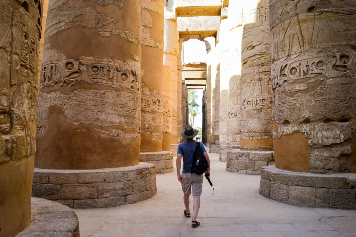 Reisender mit optimaler Kleidung zwischen mehreren Säulen in einem Tempel während seinem Ägypten Urlaub