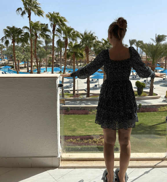 Frau steht auf dem Balkon einer ägyptischen Hotelanlage und trägt ein luftiges Kleid