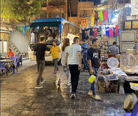 Personen und ein Reisebus auf einem Basar in Kairo mit Kindern