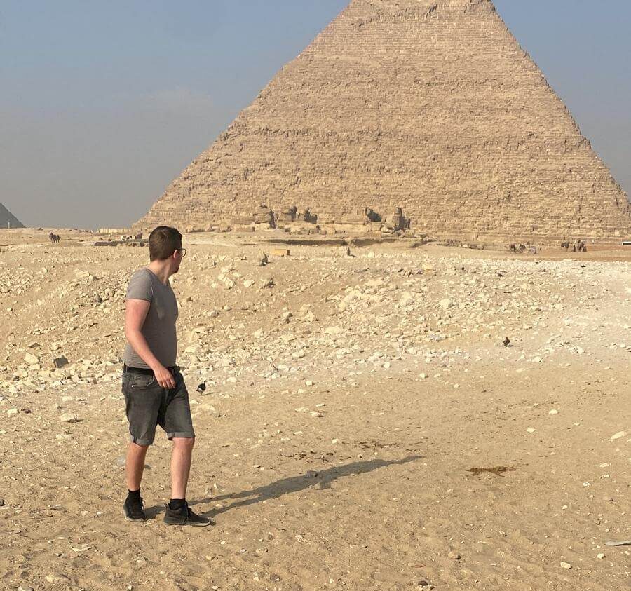 Junger Reisender trägt schwarze Sneaker vor einer der Giza Pryamiden