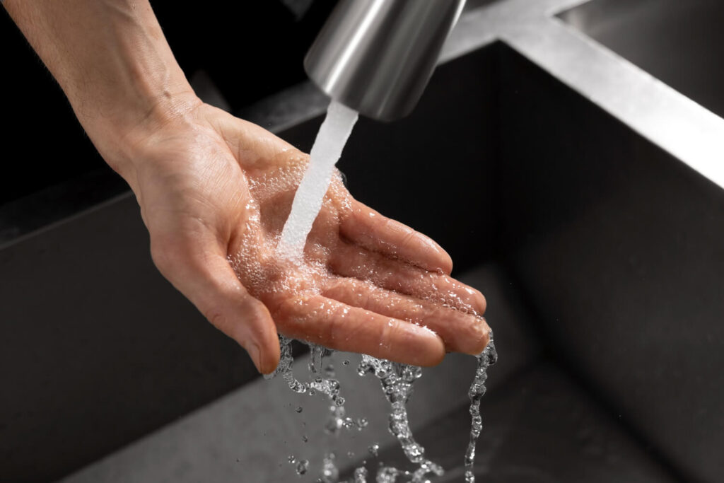 Hand unter Wasserhahn die mit Leitungswasser in Ägypten gewaschen wird
