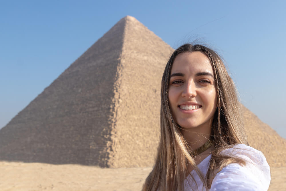 Eine Frau die alleine nach Ägypten reist posiert vor einer Pyramide