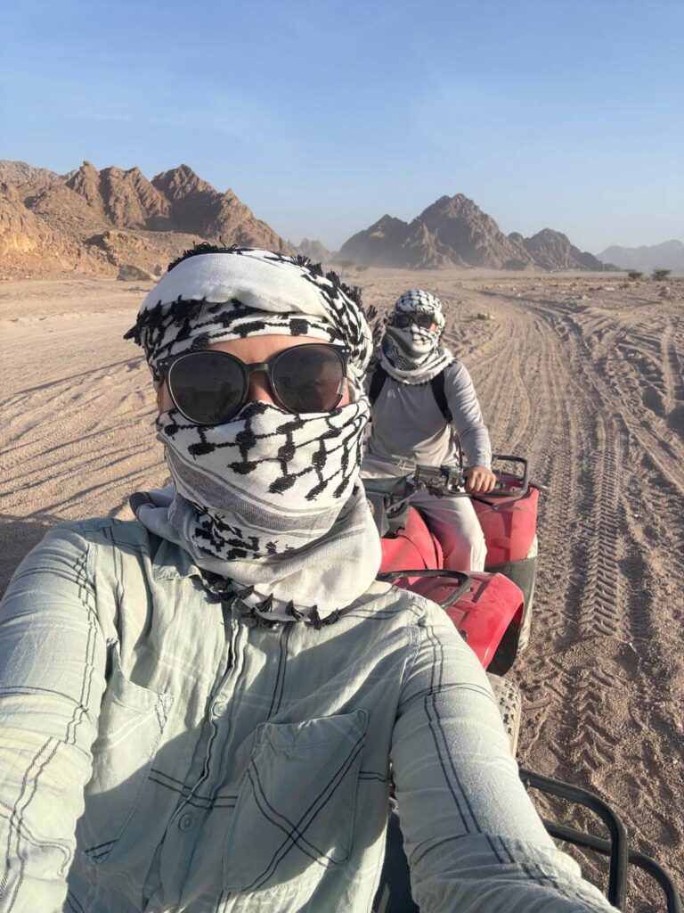 Pärchen mit weißem Schal und Sonnenbrille hinteraindner auf Quads mitten in der Wüste