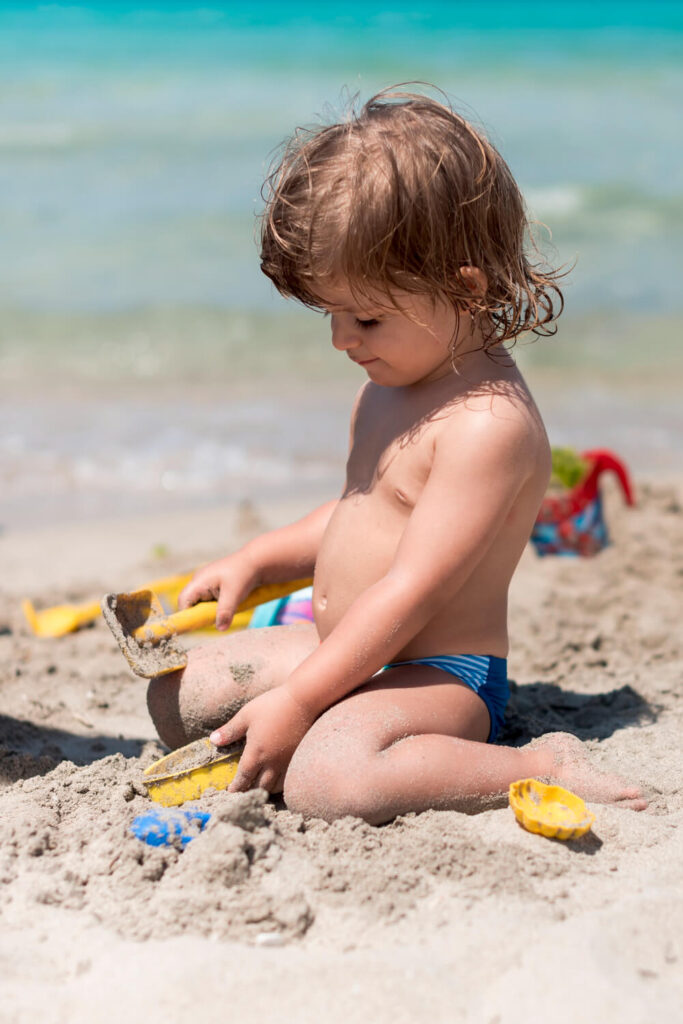 Kind spielt mit seinem Strandspielzeug im Sand