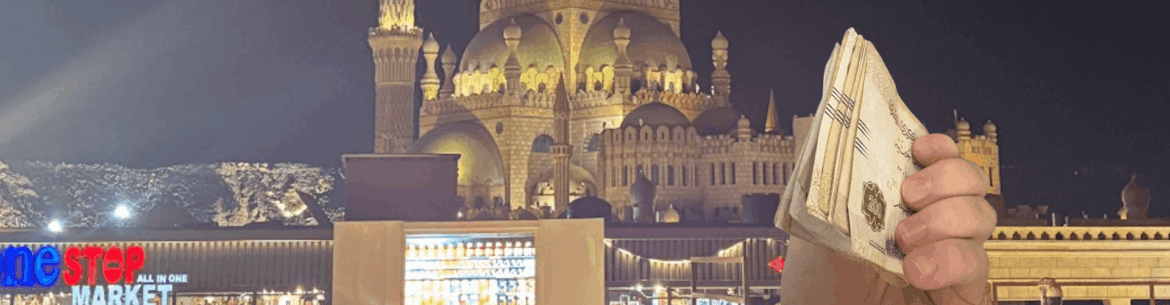 Hand hält frisch gewechseltes Geld in Ägypten in der Hand im Hintergrund Mosche Sharm El Sheikh
