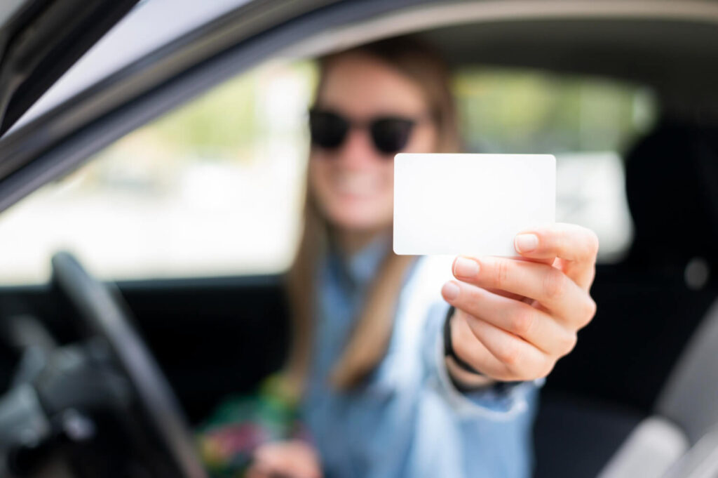 Junge blonde Touristin zeigt ihren internationalen Führerschein in Ägypten in die Kamera
