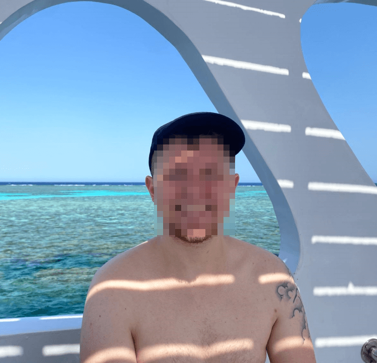 Tourist trägt eine schwarze Cap als Sonnenschutz auf einem Tauchboot